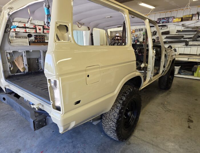 Driver side profile of restored 1988 Toyota Land Cruiser FJ62 V8 in Desert Tan with lifted suspension and black steel wheels