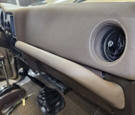 Custom Toyota Land Cruiser FJ60 dashboard with tan leather-wrapped dash, contrast stitching, and transfer case shifters