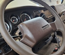 Custom Toyota Land Cruiser FJ60 interior with brown leather-wrapped steering wheel, custom gauge cluster.